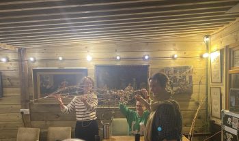 Three people hold up a beautiful creation made with willow. The first steps in creaing a beautilf dragon-fly lantern.